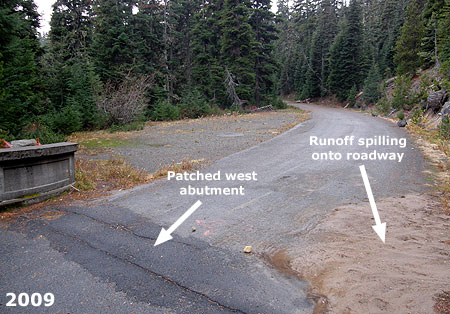 Repeated repairs to the abutment and debris washed onto the roadway is apparent in this 2009 view of the west approach to the bridge