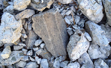 In a nearby pile of demolition rubble, chunks of the old railing cap show the quarter round detail that follows the outer edge of the caps