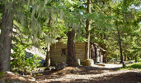 The Upper Sandy Guard Station sits on a flat bench above the Sandy River, just off the modern alignment of the Pacific Crest Trail.