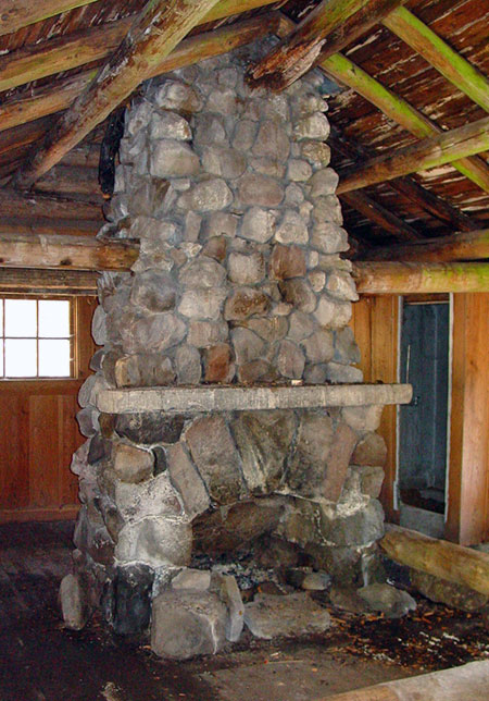 This magnificent fireplace stands at the center of the guard station; the room in the background is a built-in shower, lined with galvanized steel.